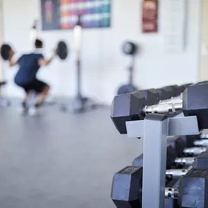 Blick in den Fitnessraum in Offenbach mit verschiedenen Hanteln, im Hintergrund nutzt ein Mitarbeiter eine Hantelstange.