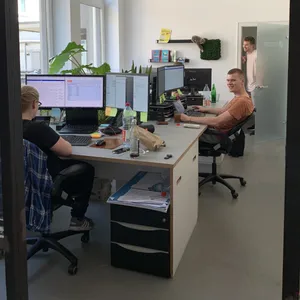 Zwei Mitarbeiter arbeiten konzentriert an ihren Bildschirmen in einem hellen Büro.