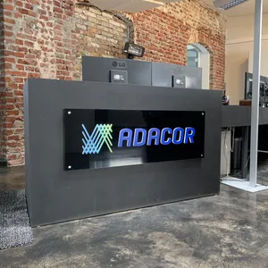 Empfangstresen mit dem Adacor Logo steht vor einer Backsteinwand.